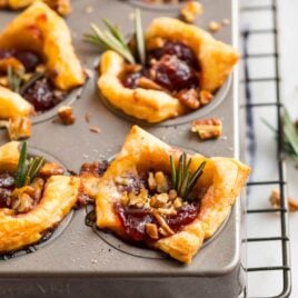 Brie bites in a muffin tin with fresh herbs