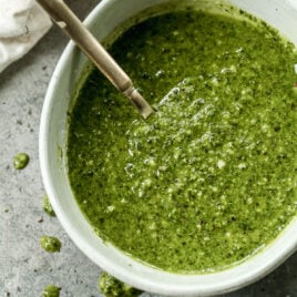 A bowl of basil pesto with a spoon